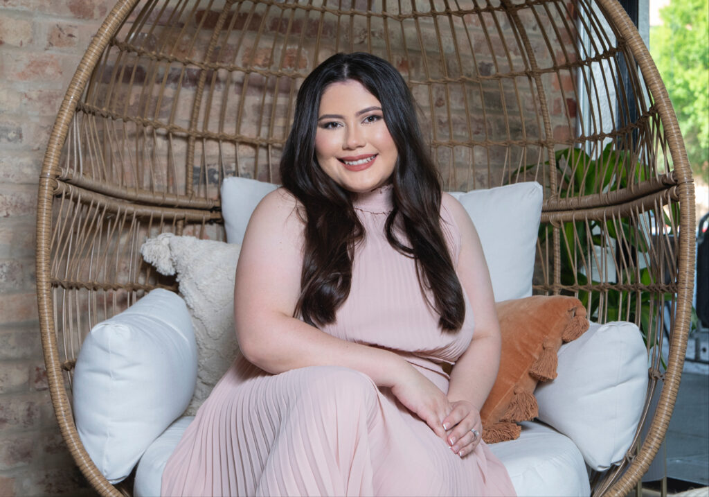 Woman in pink dress sitting on a rattan whicker chair.